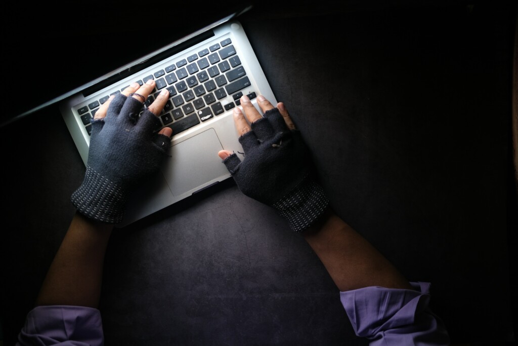 gloved hands typing on a laptop computer