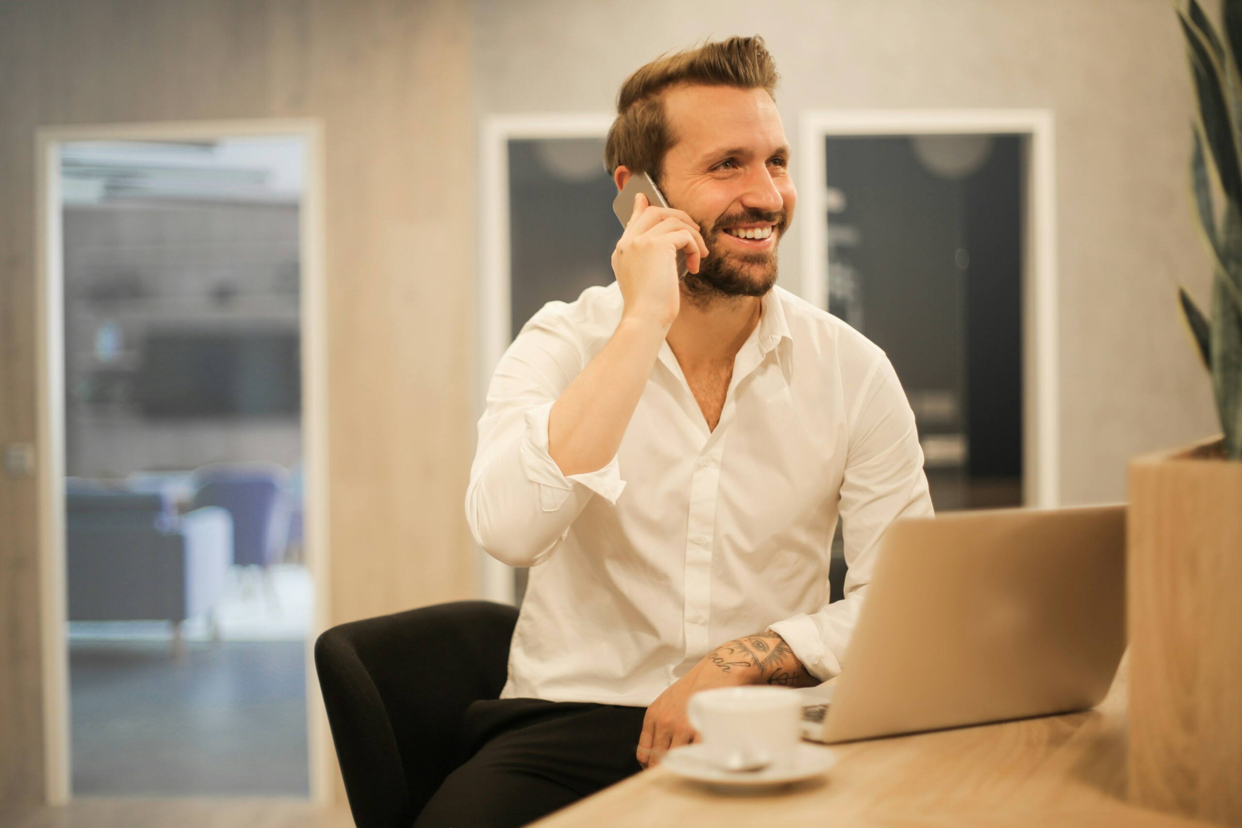 male talking on phone at desk with computer